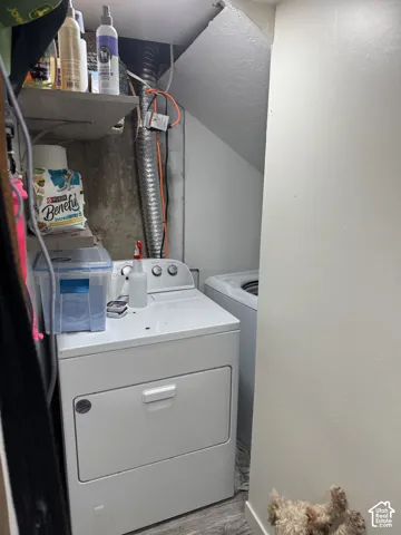 Laundry in basementbalcove featuring wood-finish flooring and built-in shelving