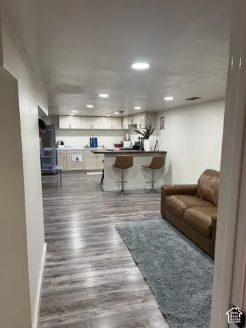 Kitchen in basement featuring wood-finish flooring, white cabinetry, a countertop peninsula, and recessed ceiling lighting