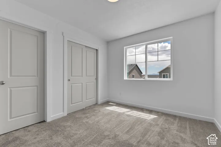 Neutral-toned interior featuring wall-to-wall carpeting, paneled interior doors, and a multi-pane window