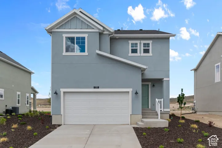 Two-story exterior featuring a light blue stucco finish, white trim detailing, a concrete driveway, an attached garage, and a covered front entryway with white railing