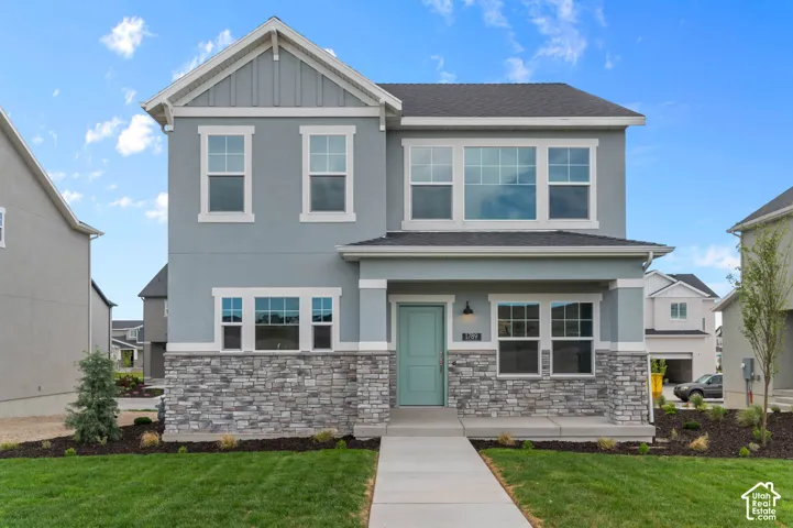 Two-story exterior featuring a stone veneer facade, vertical siding accents, covered front porch, and multi-pane windows