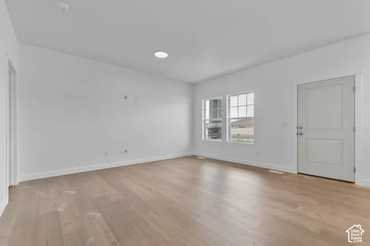 Interior room featuring wood-finish flooring, white walls, dual pane windows, and a solid-core entry door
