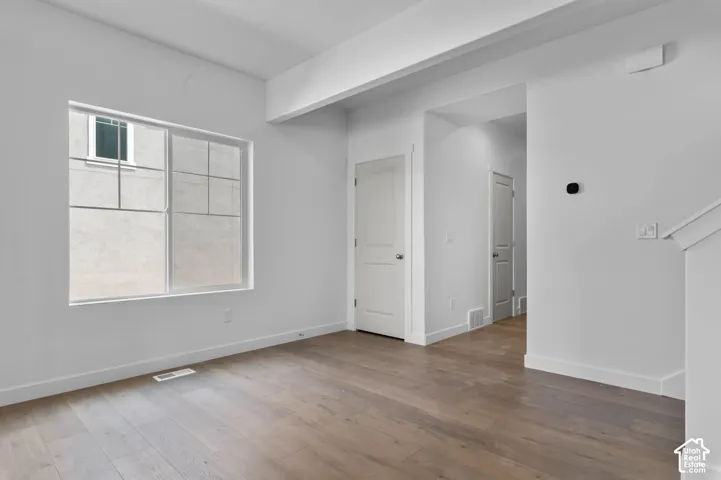 Interior space featuring wood-finish flooring, white walls, and a large multi-pane window