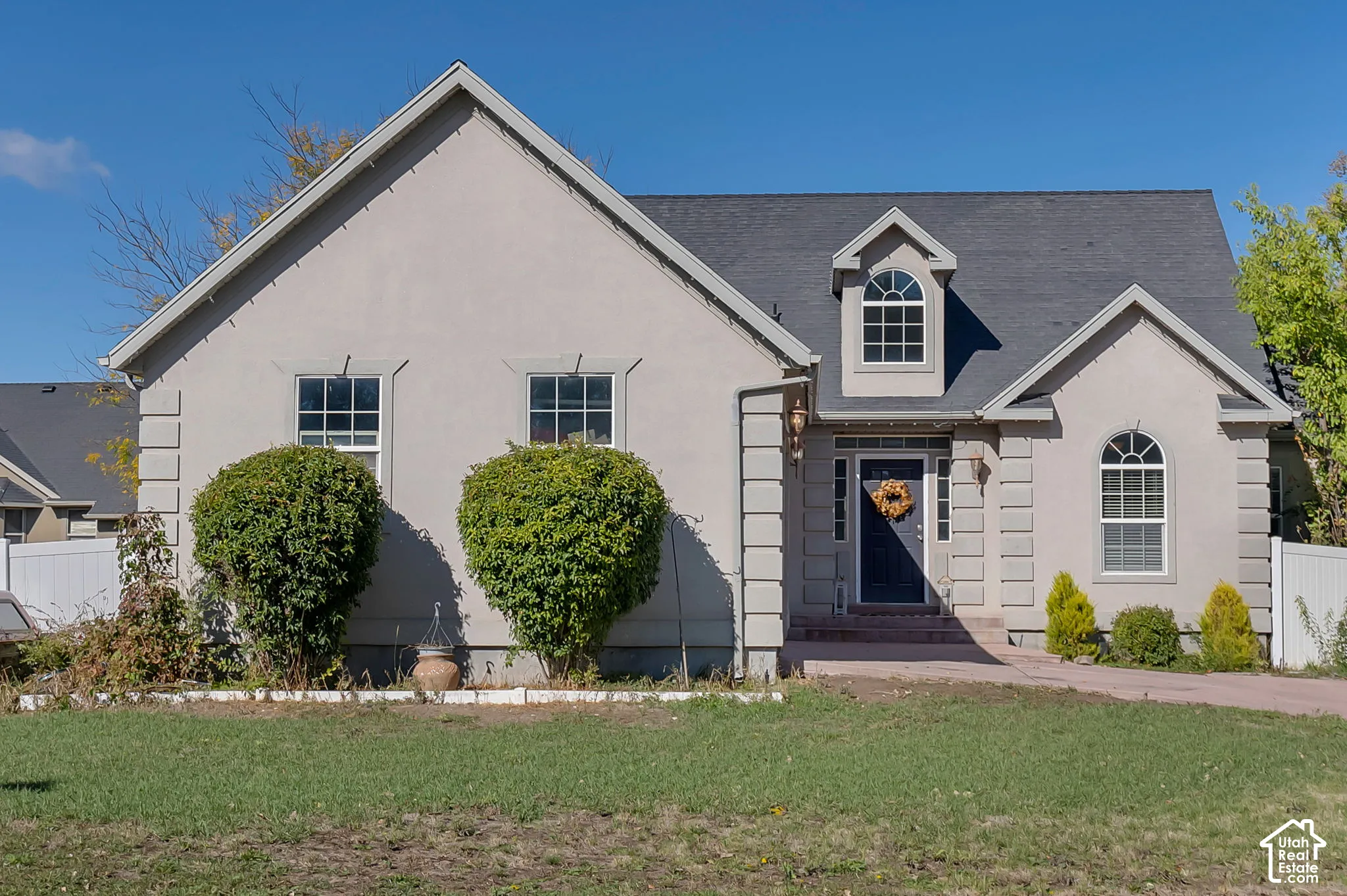 Stucco exterior featuring quoined corner detailing, arched windows, a dormer window, and asphalt shingle roofing