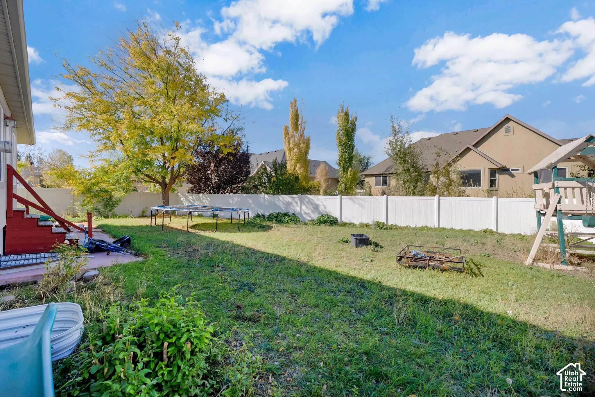 Rear yard featuring a grass lawn, perimeter vinyl fencing, and mature trees