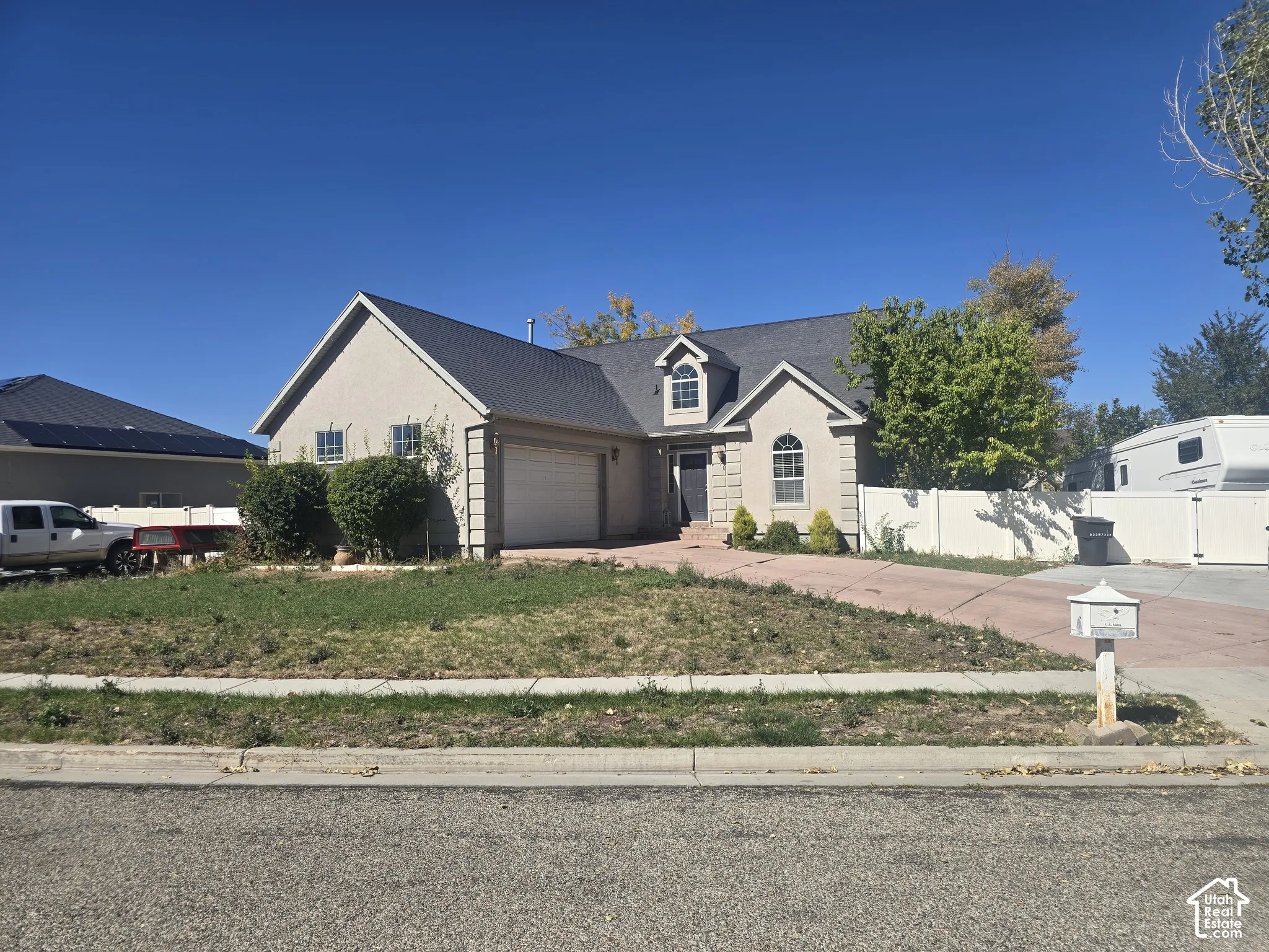 Stucco exterior with an attached garage, arched windows, and a black shingle roof