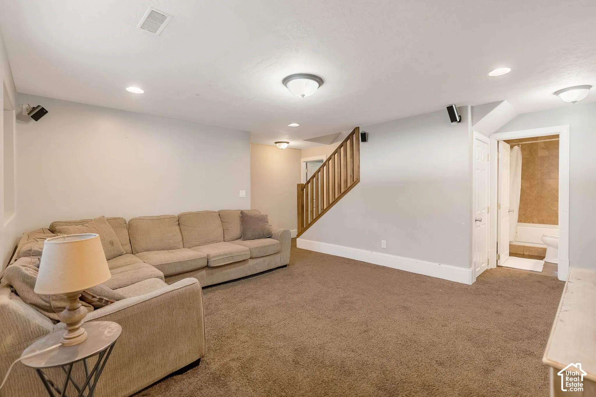Neutral wall tones, recessed lighting, wood-finish staircase railing, and carpeted flooring