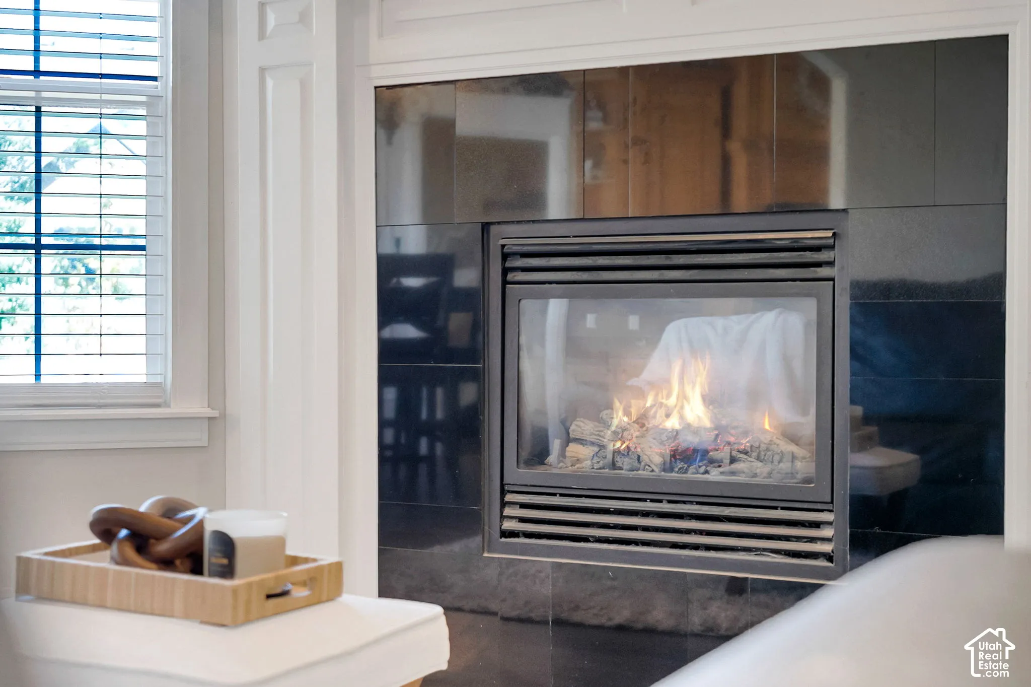 Fireplace with a black tile surround, white fluted trim detailing, and a glass-front insert