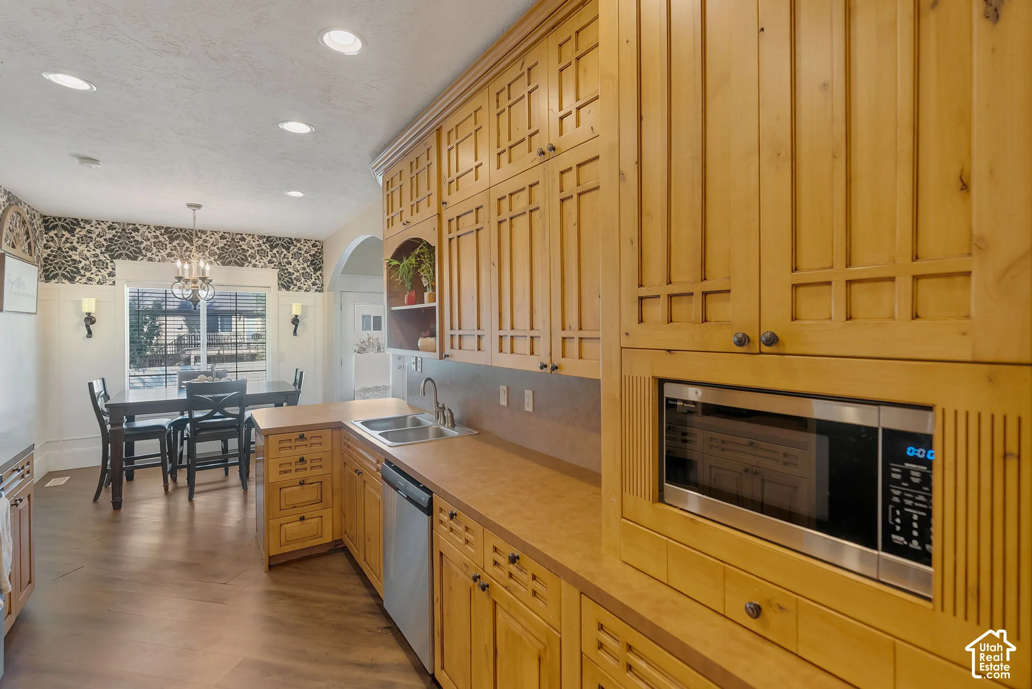 Custom wood cabinetry with geometric panel detailing, integrated microwave, recessed lighting, and wood-finish flooring