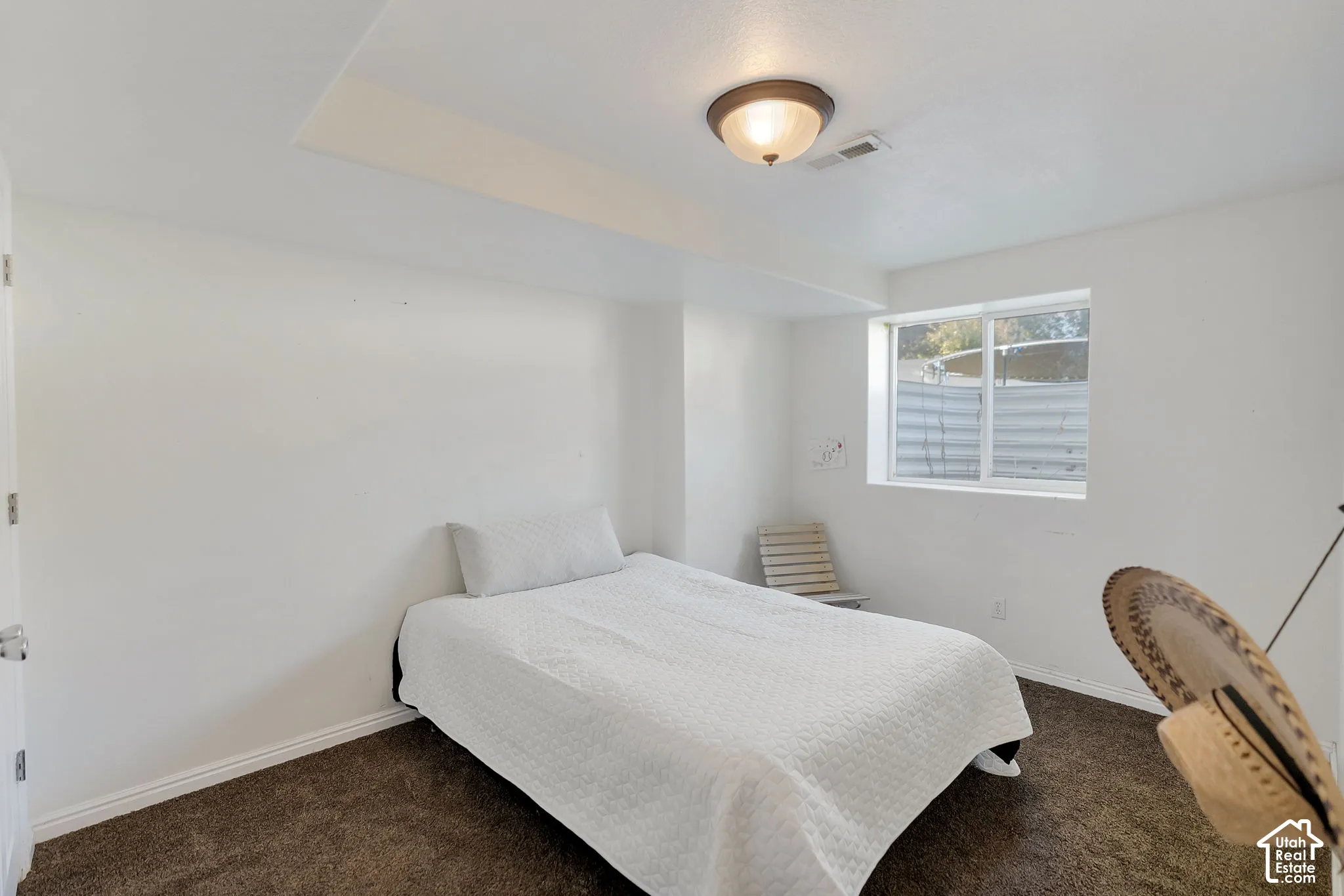 Neutral-toned room featuring dark carpeting, a recessed ceiling detail, and a white-framed slider window