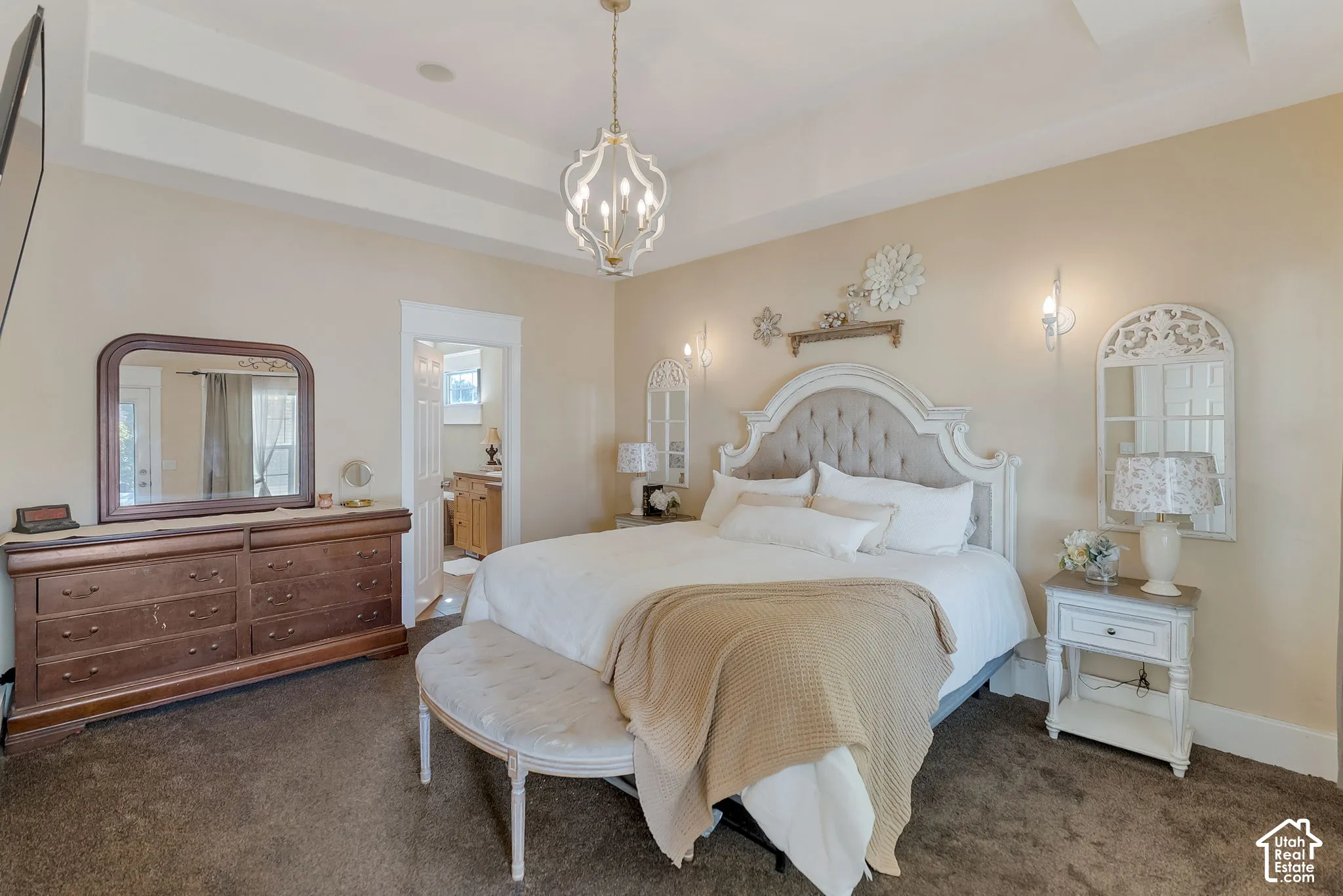 Tray ceiling featuring a polished metal lantern chandelier, wall-mounted light fixtures, and carpeting