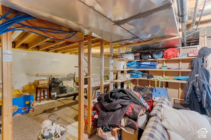 Unfinished lower level featuring exposed wood joists, structural support framing, and built-in wood shelving