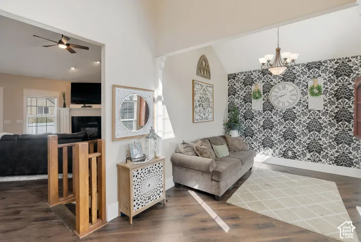 Vaulted ceilings, wood-finish flooring, a tiered chandelier, decorative patterned wallpaper, and wood-railing staircase