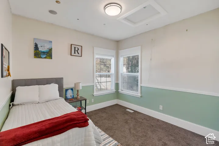 Interior room featuring two windows with white trim, chair rail molding, carpeted flooring, and a flush-mount light fixture