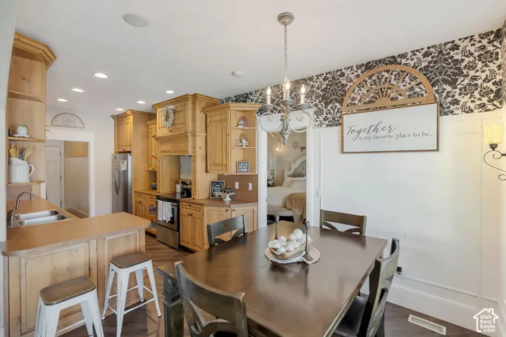 Kitchen featuring custom natural wood cabinetry, recessed lighting, wood-finish flooring, and a peninsula with a stainless steel sink