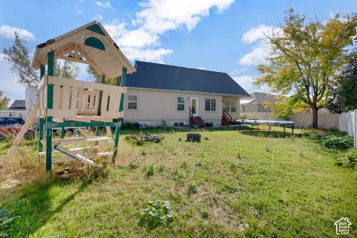 Rear exterior featuring a gabled roof, light-toned siding, white-trimmed windows, and perimeter privacy fencing