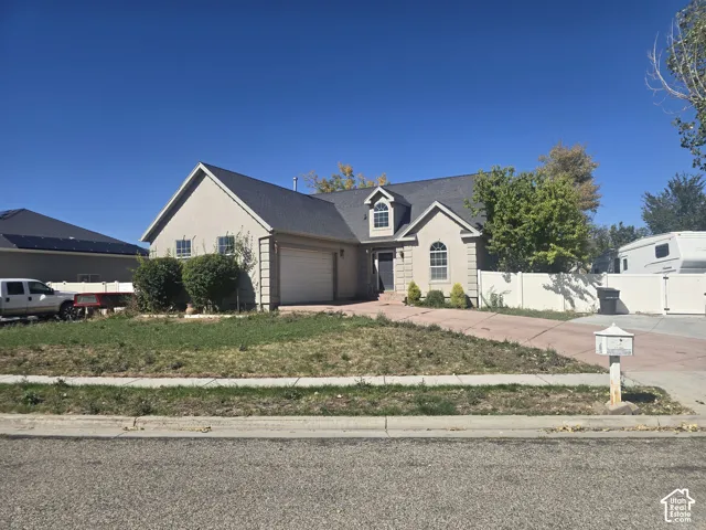 Stucco exterior with an attached garage, arched windows, and a black shingle roof
