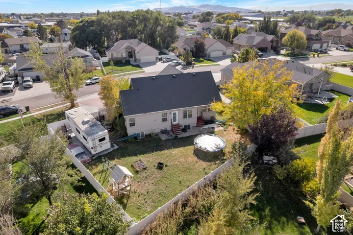 Aerial perspective featuring a fenced backyard, mature trees, and mountain backdrop