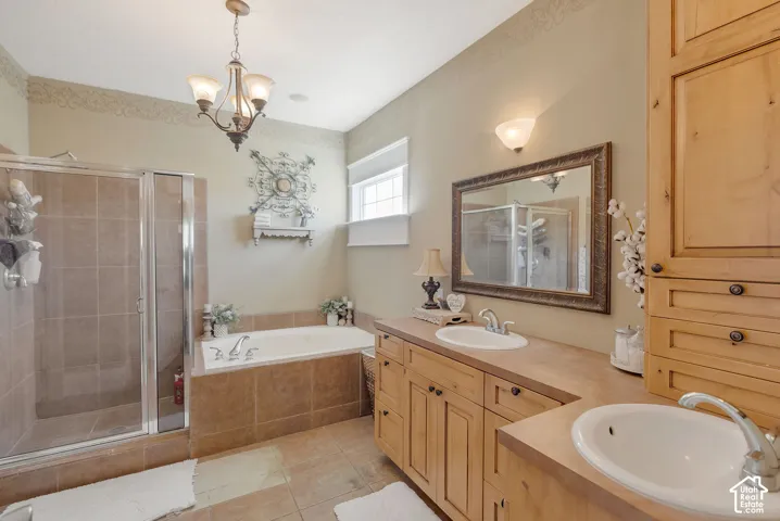 Bathroom featuring natural wood cabinetry, dual drop-in sinks, a separate soaking tub with tile surround, and a glass-enclosed shower