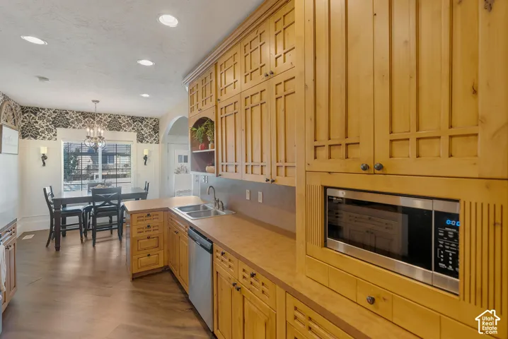 Custom wood cabinetry with geometric panel detailing, integrated microwave, recessed lighting, and wood-finish flooring