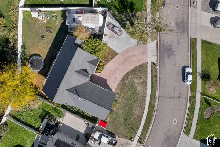 Aerial view of property featuring a curved concrete driveway, asphalt shingle roofing, and a fenced rear yard
