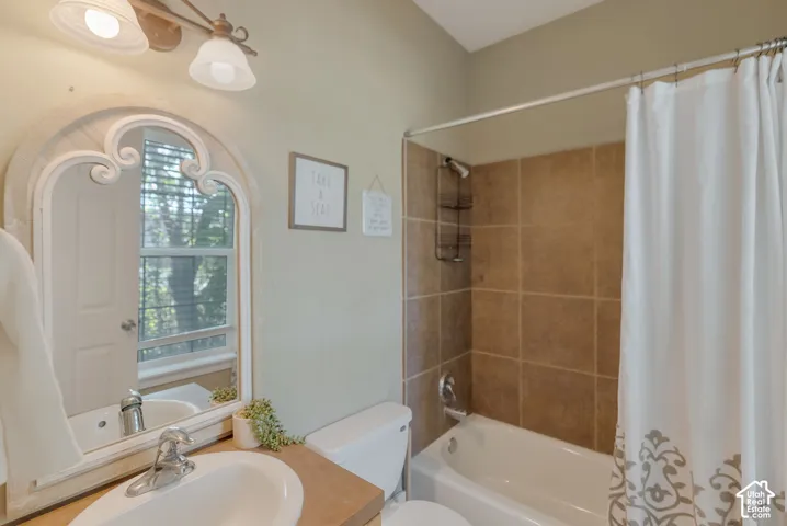Bathroom featuring a vanity with an integrated sink, an arched decorative mirror, a dual-light fixture, and a tub-shower combination with floor-to-ceiling tile surround