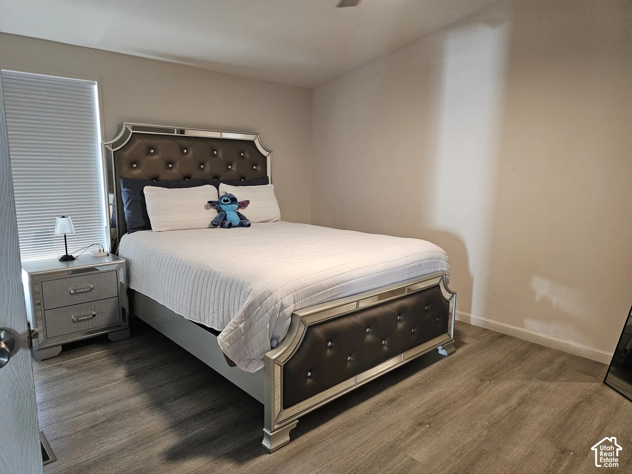 Neutral-toned room featuring wood-finish flooring and a window with pleated cellular shades
