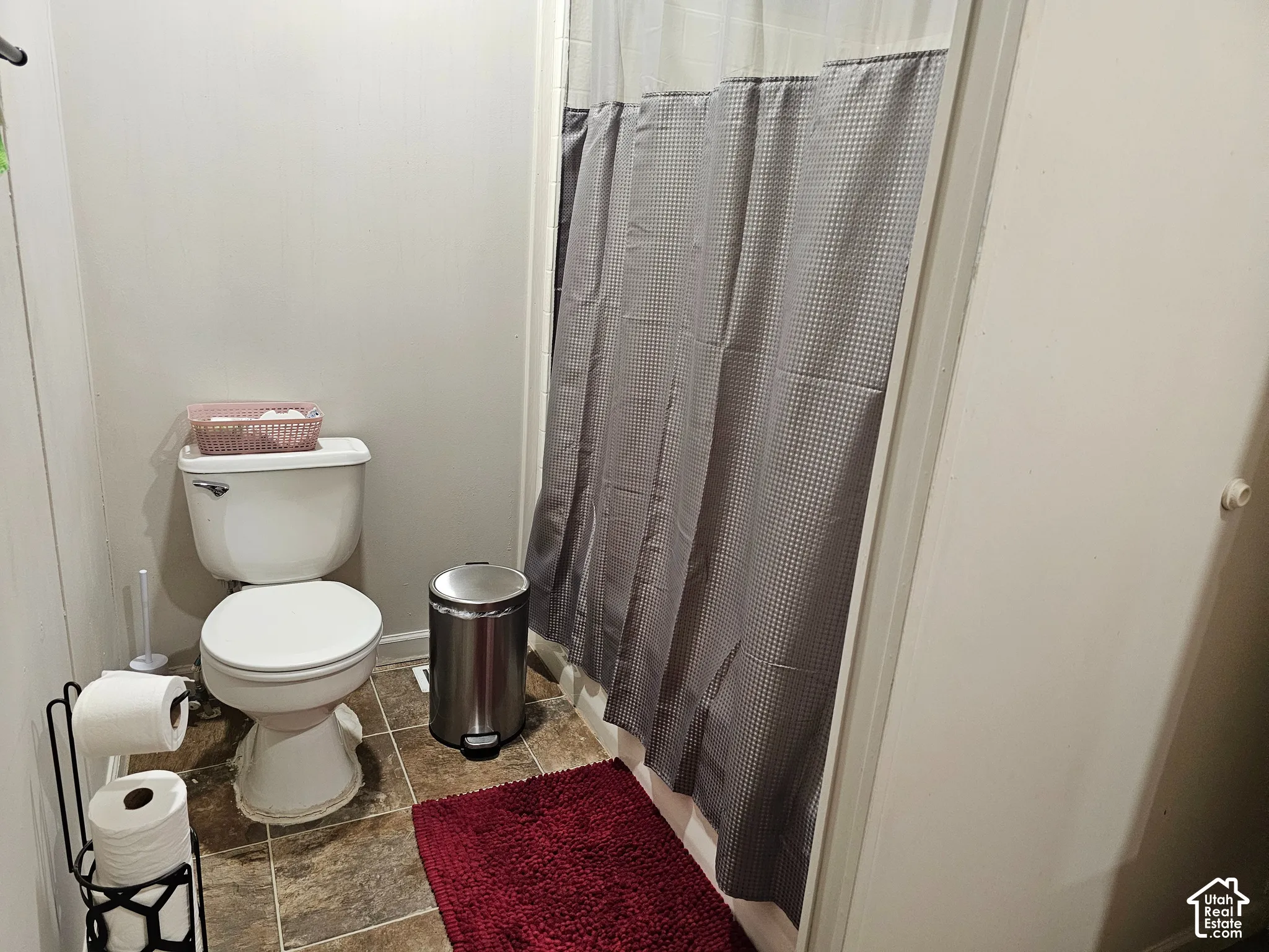Bathroom featuring a standard white porcelain toilet and shower-tub combination with a shower curtain enclosure, complemented by tile flooring