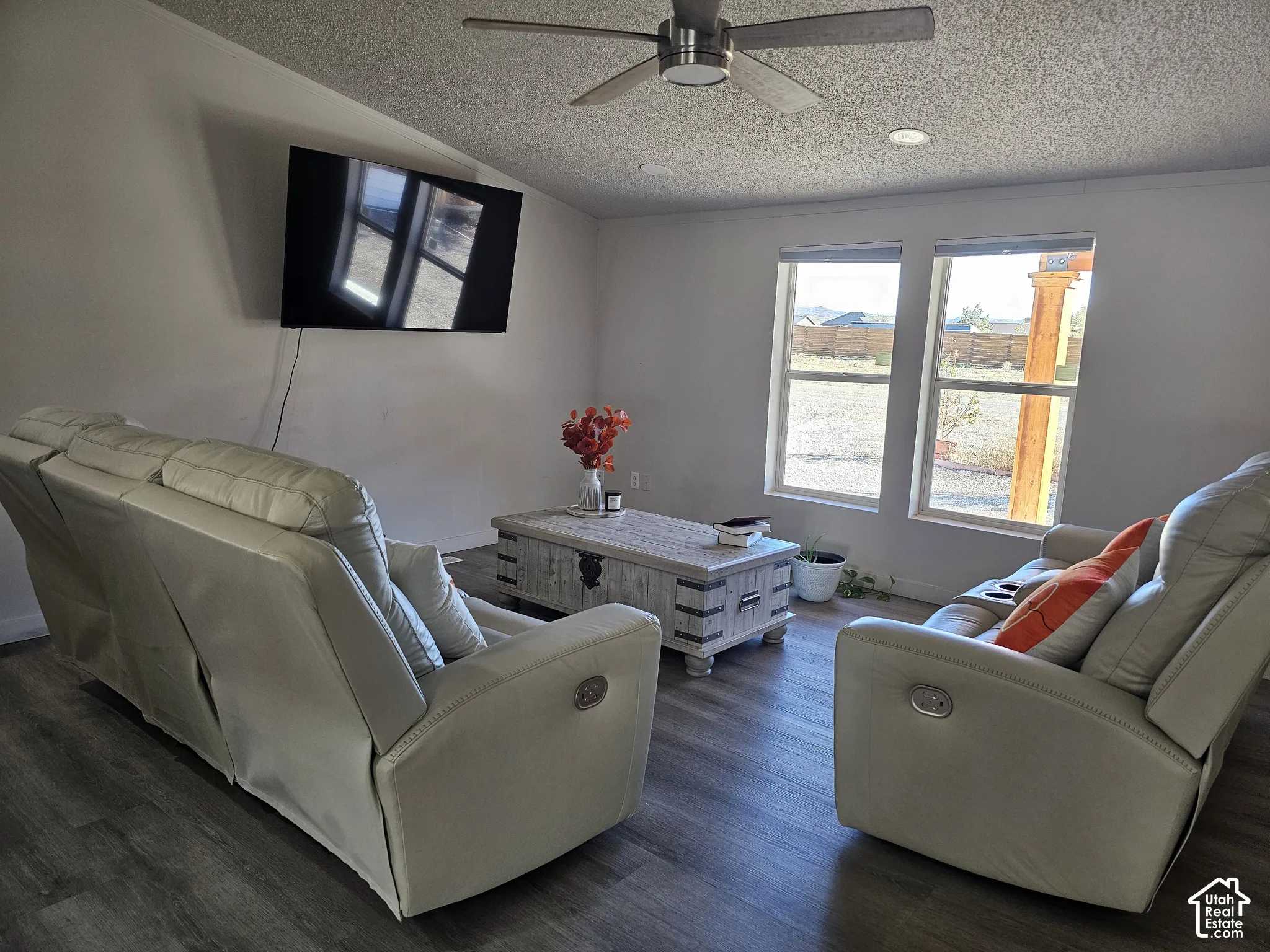 Living area featuring wood-finish flooring, dual-pane windows, a recessed ceiling fan with integrated lighting, and textured ceiling finish