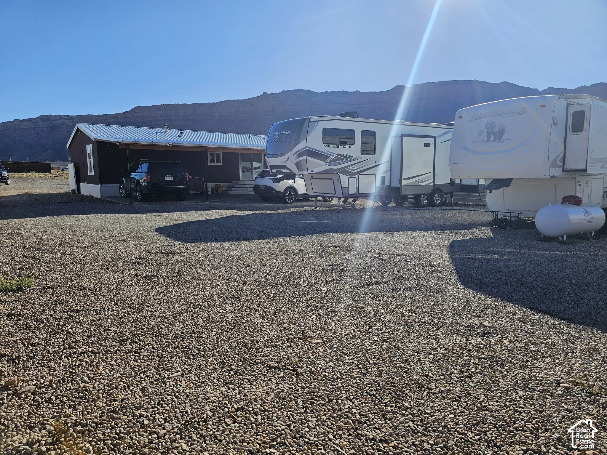 Expansive gravel-surfaced lot featuring a metal roof structure and mountain backdrop