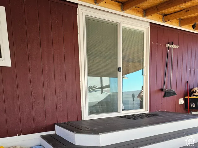 Multi-tiered exterior steps featuring dark composite decking and white risers, glass sliding door, and vertical panel siding