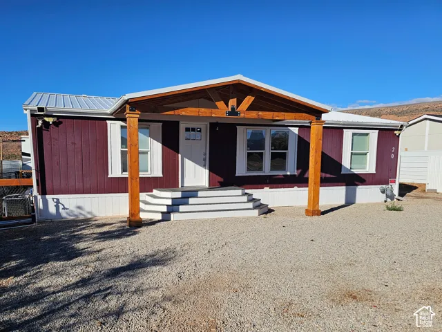 Exterior featuring metal roofing, a timber-framed covered entryway, exterior wood-finish siding, and a multi-step staircase