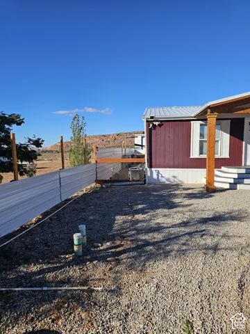Exterior featuring metal siding, a covered porch with timber support posts, a metal roof, and corrugated metal perimeter fencing