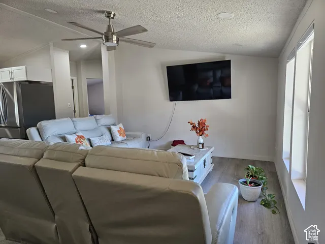 Vaulted ceilings, brushed-nickel ceiling fan, recessed lighting, and wood-finish flooring