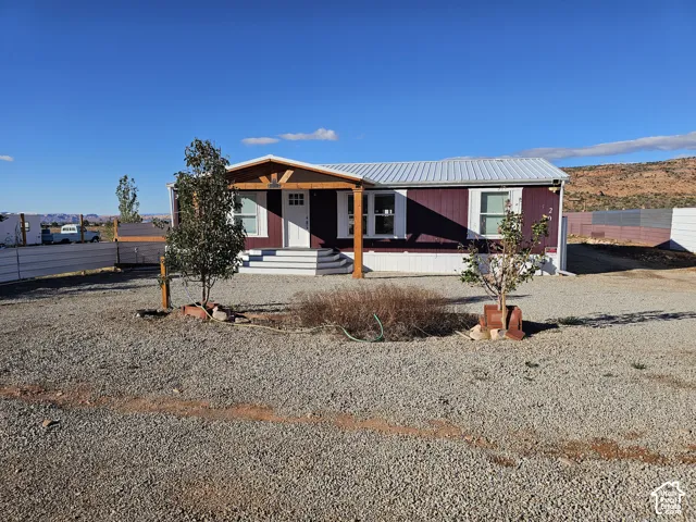 Exterior featuring a metal roof, covered front porch with timber-frame support posts, and gravel grounds
