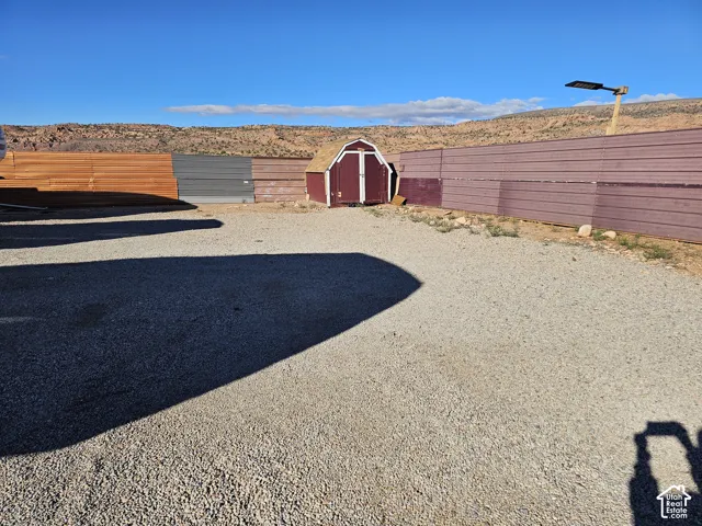 Gravel-surfaced exterior lot featuring a detached storage shed and corrugated metal perimeter fencing