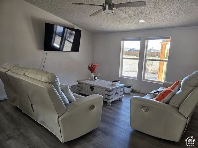 Living area featuring wood-finish flooring, dual-pane windows, a recessed ceiling fan with integrated lighting, and textured ceiling finish