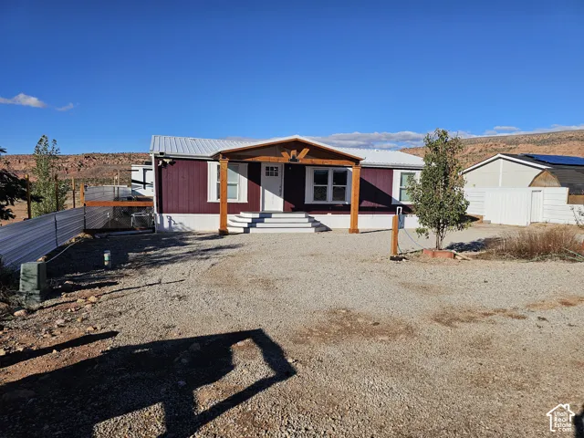 Single-story residence featuring a metal roof, wood-post covered entryway, multi-pane front door, and gravel surfacing