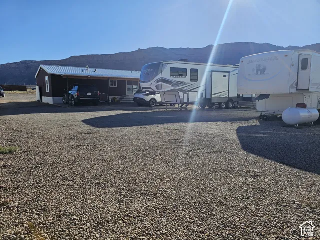Expansive gravel-surfaced lot featuring a metal roof structure and mountain backdrop