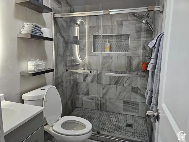 Walk-in shower featuring large-format wall tile, a hexagonal mosaic tile floor, an integrated wall niche, and a glass sliding door