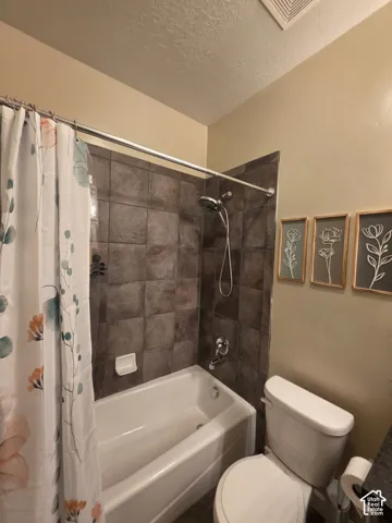 Full-height dark-toned square tile shower surround, chrome handheld shower head, and built-in ceramic soap dish