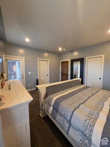 Room featuring recessed lighting, carpeted flooring, two interior panel doors, and a wood-textured door with decorative hardware