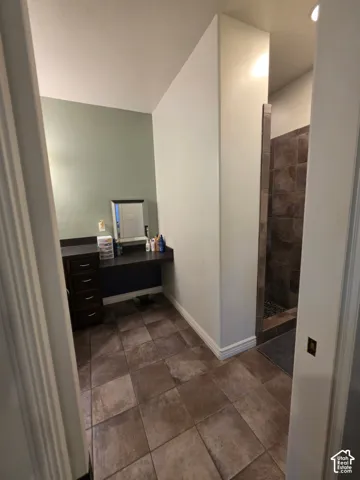 Dark-finish cabinetry with a solid-surface countertop, tile flooring, and walk-in shower with tiled walls