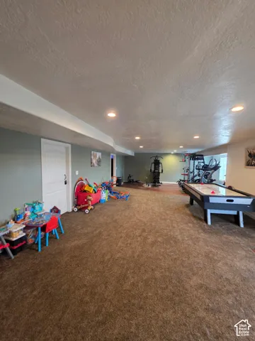Spacious room featuring recessed lighting, neutral-tone carpeting, and a white six-panel door