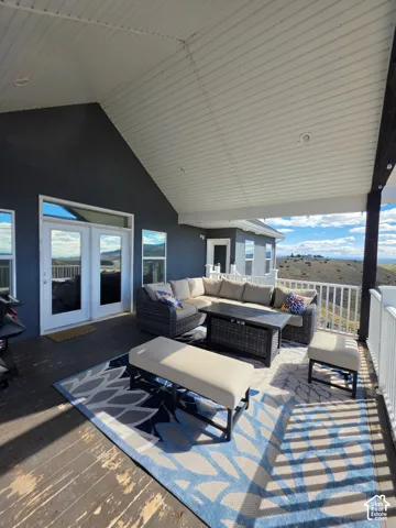 Covered exterior deck featuring wood-finish decking, vaulted beadboard ceiling with recessed lighting, white railing, and exterior mountain scenery