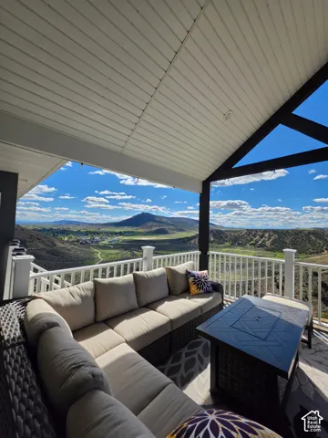 Covered outdoor deck featuring a vaulted tongue-and-groove ceiling, dark-stained exposed timber framing, and white vertical balustrade railings with expansive mountain scenery