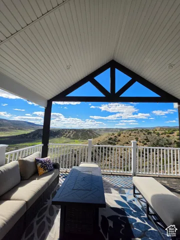 Covered outdoor deck featuring a vaulted gable ceiling, dark timber truss detailing, recessed lighting, and white balustrade railing