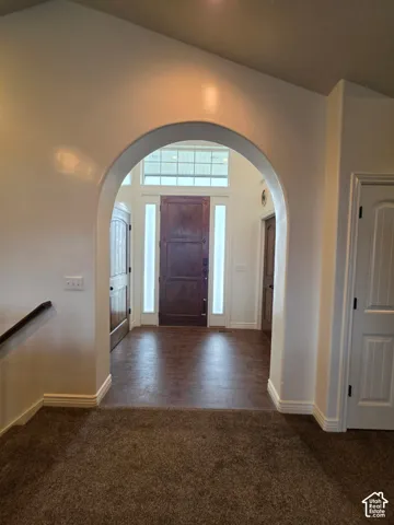 Entryway featuring a structural arched opening, wood-finish front door with dual sidelights, overhead transom window, and tile flooring