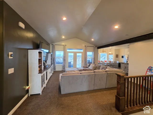 Vaulted ceilings, dark accent wall, recessed lighting, carpeted flooring, and wood-railing staircase