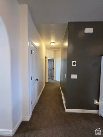 Interior hallway featuring neutral carpet flooring, an arched entryway, accent-painted wall, and two-panel interior doors